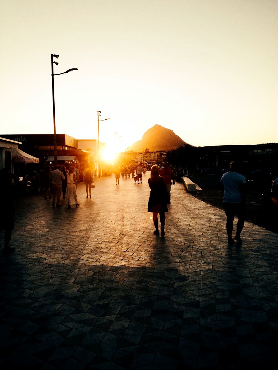 Evening paseo on the Arenal promenade as the sun sets behind Montgó