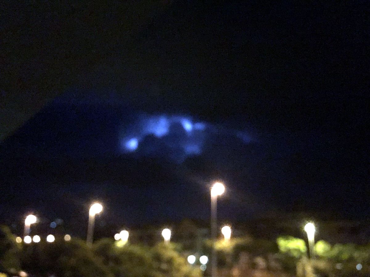 Night silhouette of Montgó with storm cloud lit behind the summit and streetlights below