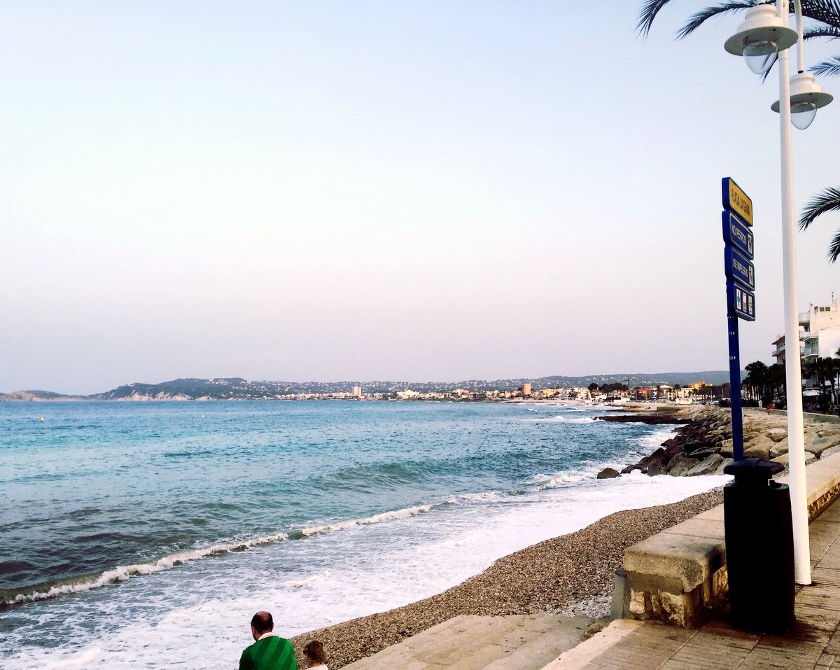 Sea-front promenade and pebble shoreline on Javea’s Muntanyar coast, looking along the bay towards the port