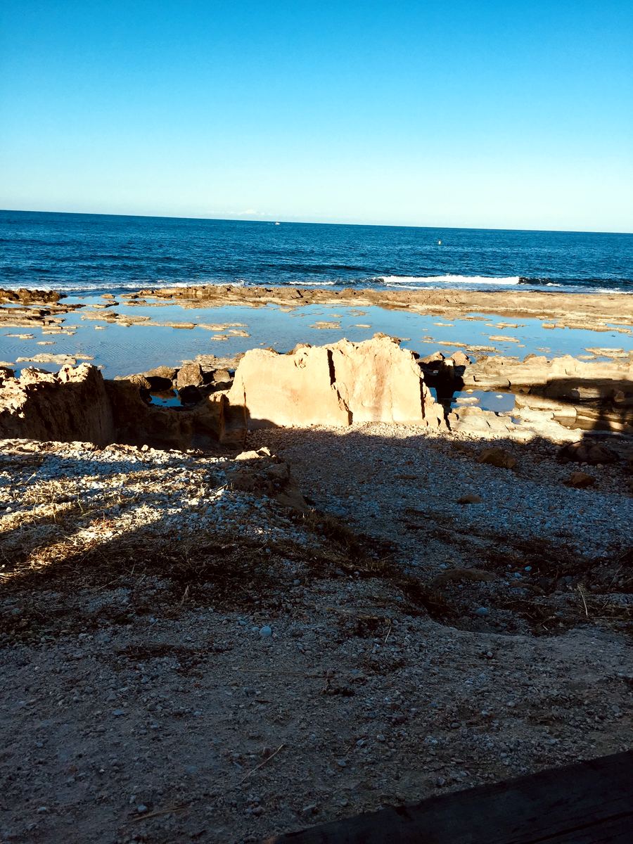 Flat tosca rock pools along the Primer Muntanyar shoreline