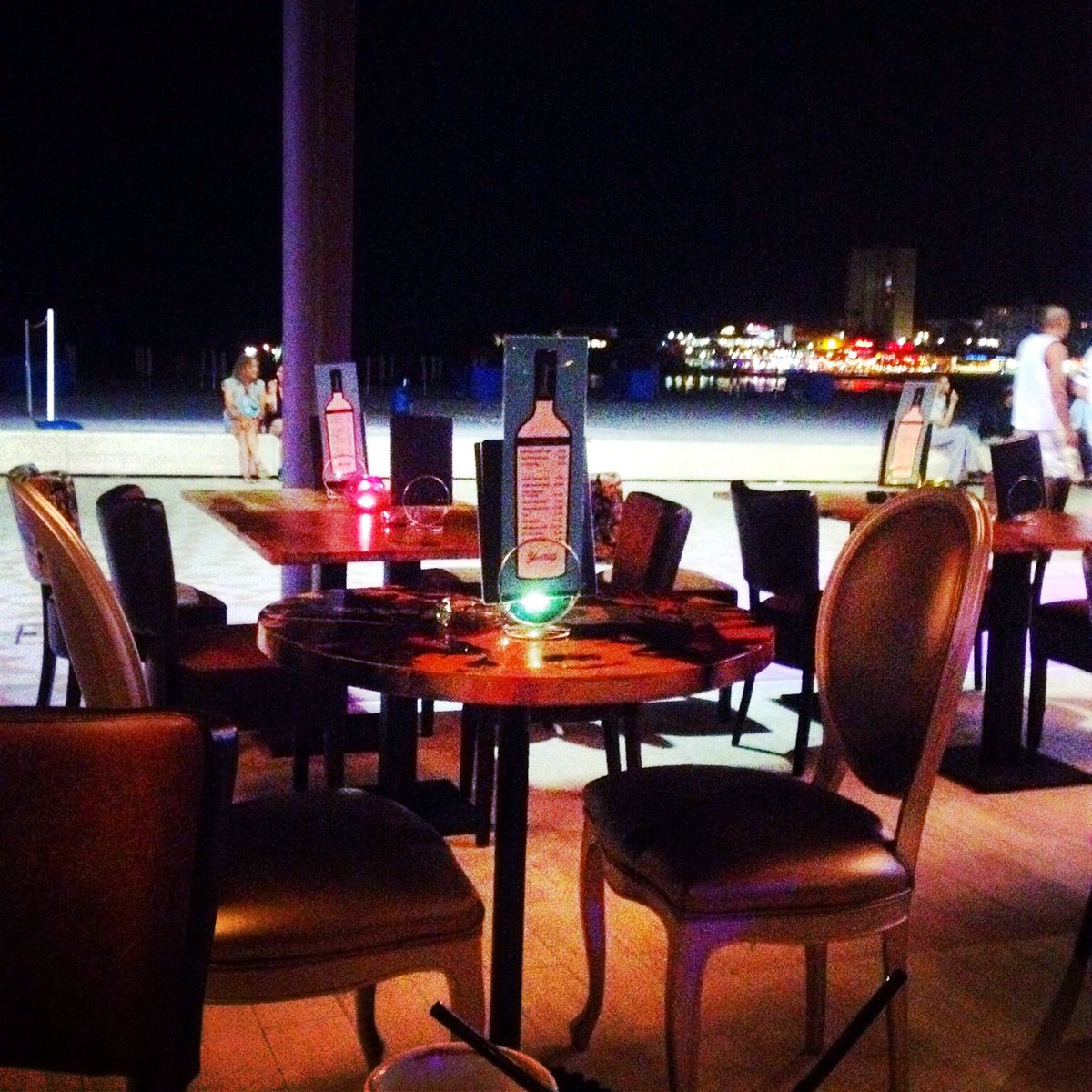 A candle-lit terrace table by the beach promenade after dark