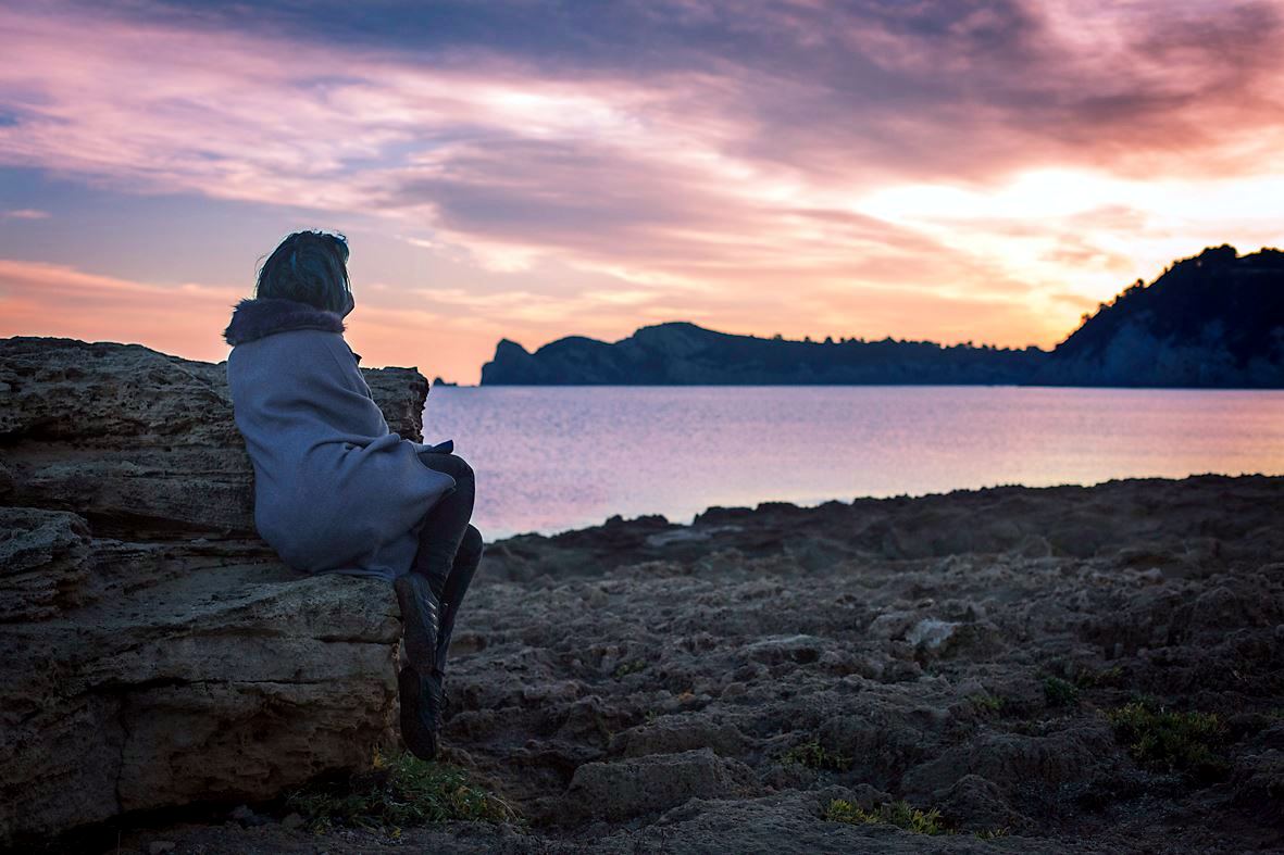 Dawn in pink and violet over a rocky Mediterranean shoreline