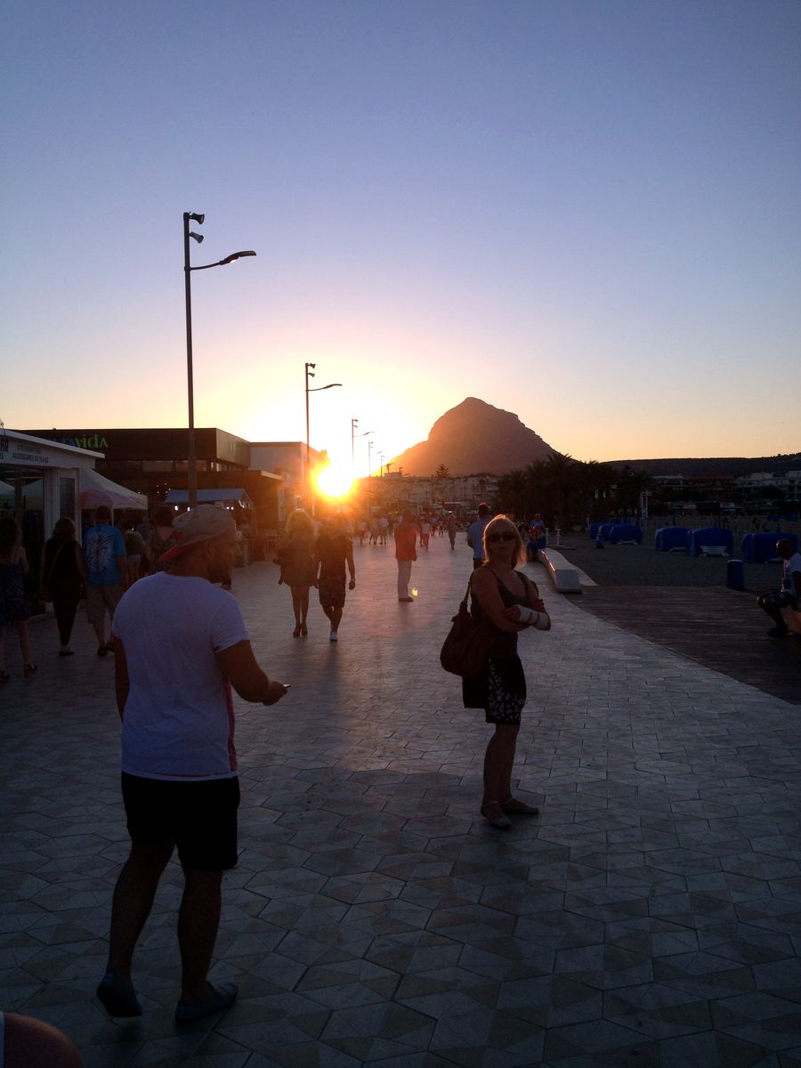 An evening stroll along the Arenal promenade as the sun drops behind Montgó